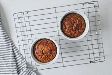 Two dog friendly cakes baked in small ramekins on wire rack.
