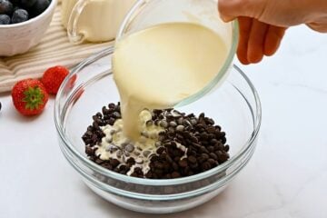 Warm cream being poured over chocolate chips to make ganache topping.