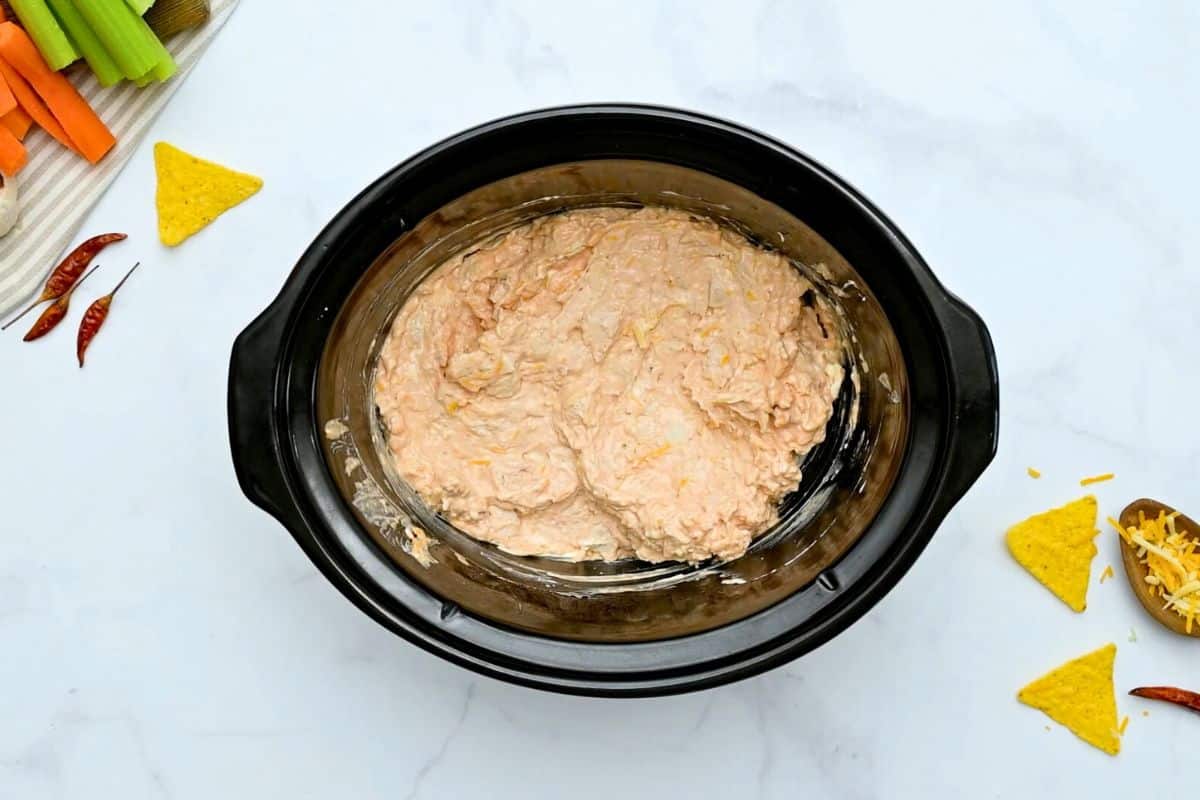 Slow Cooker Chicken Wing Dip Cubed cream cheese, ranch dressing, shredded cheese, garlic powder, hot wing sauce, and diced chicken mixed together inside liner or crockpot.