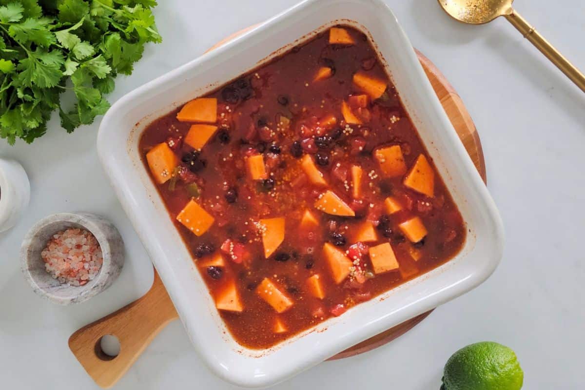 Dump and Bake Quinoa Quinoa with cubed sweet potatoes, canned black beans, diced tomatoes, vegetable broth, and taco seasoning in white dish before baking.