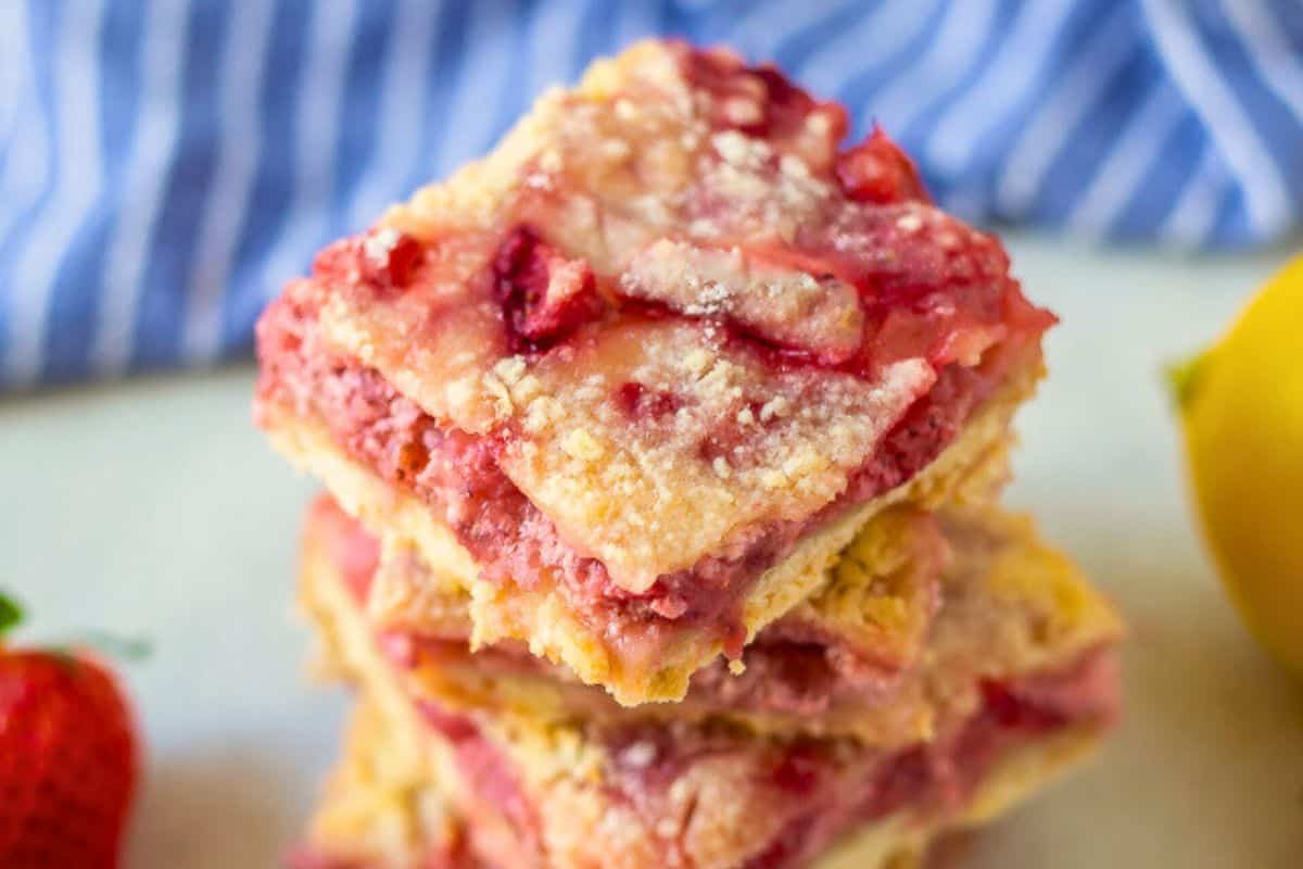 Dinner Recipes for Easter Slices of strawberry crumb bars stacked on top of eachother next to fresh strwberries.