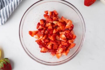 Diced strawberries in medium mixing bowl tossed with a bit of strawberries.