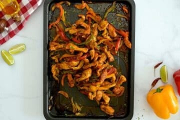 Chicken and peppers with onions roasted on sheet pan topped after finishing with lime zest and lime juice.