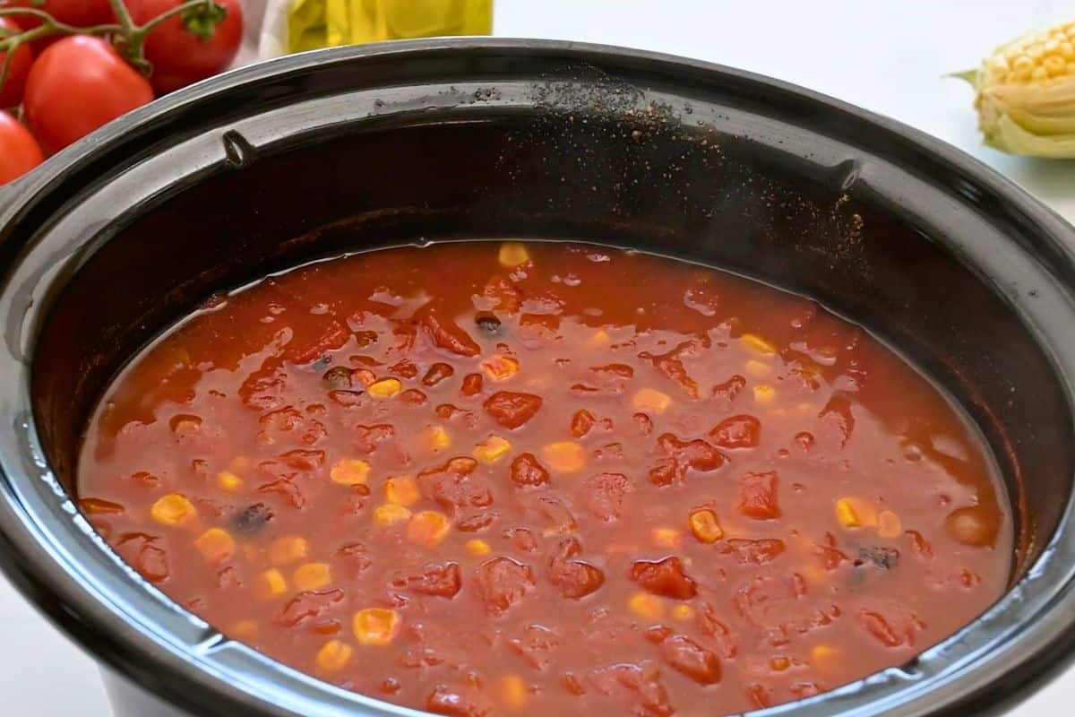 Easy Crockpot Tortilla Soup Recipe Slow cooker with cooked tortilla soup made with chicken breasts, beans, and corn, and a spiced tomato broth.