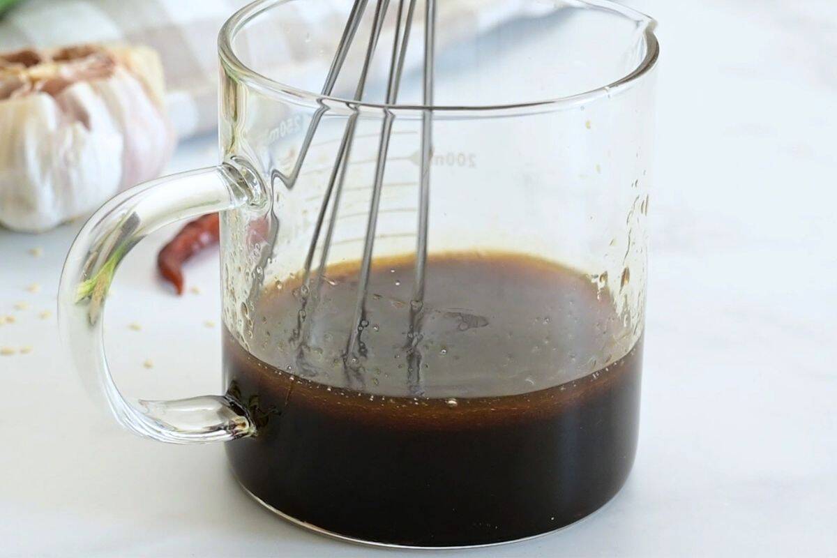 Egg Roll Bowl with Ground Turkey Soy sauce, rice vinegar, honey, sesame oil, and sriracha being whisked together in small glass measuring cup.