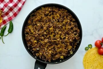 Browned beef, onions, garlic, green chiles, and enchilada sauce in skillet for enchilada casserole filling.