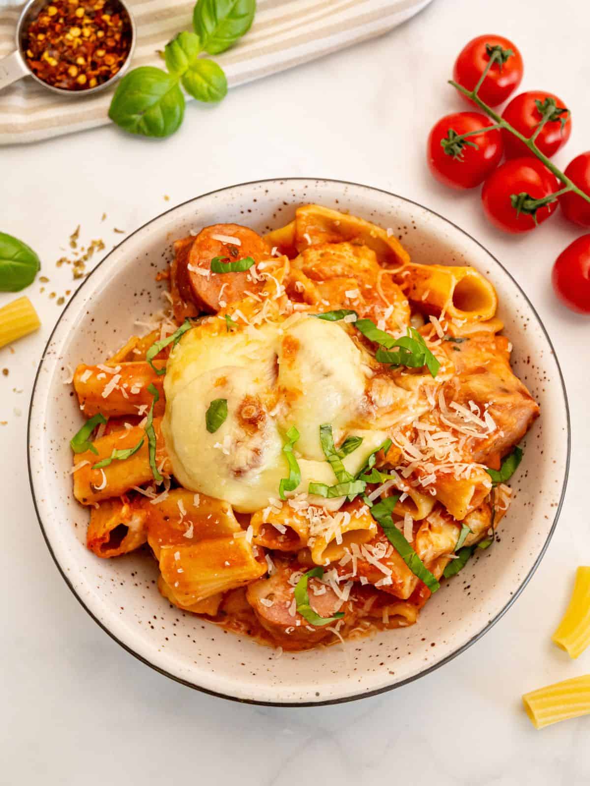No boil rigatoni pasta bake dished up in white bowl topped with ribbons of basil.