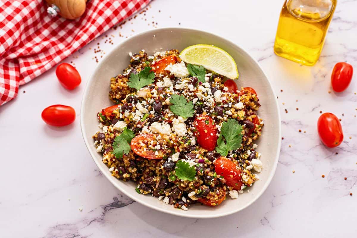 Taco bar ideas for Cinco de Mayo Party Quinoa Salad with black beans, tomatoes and cilantro, in white bowl topped with feta.
