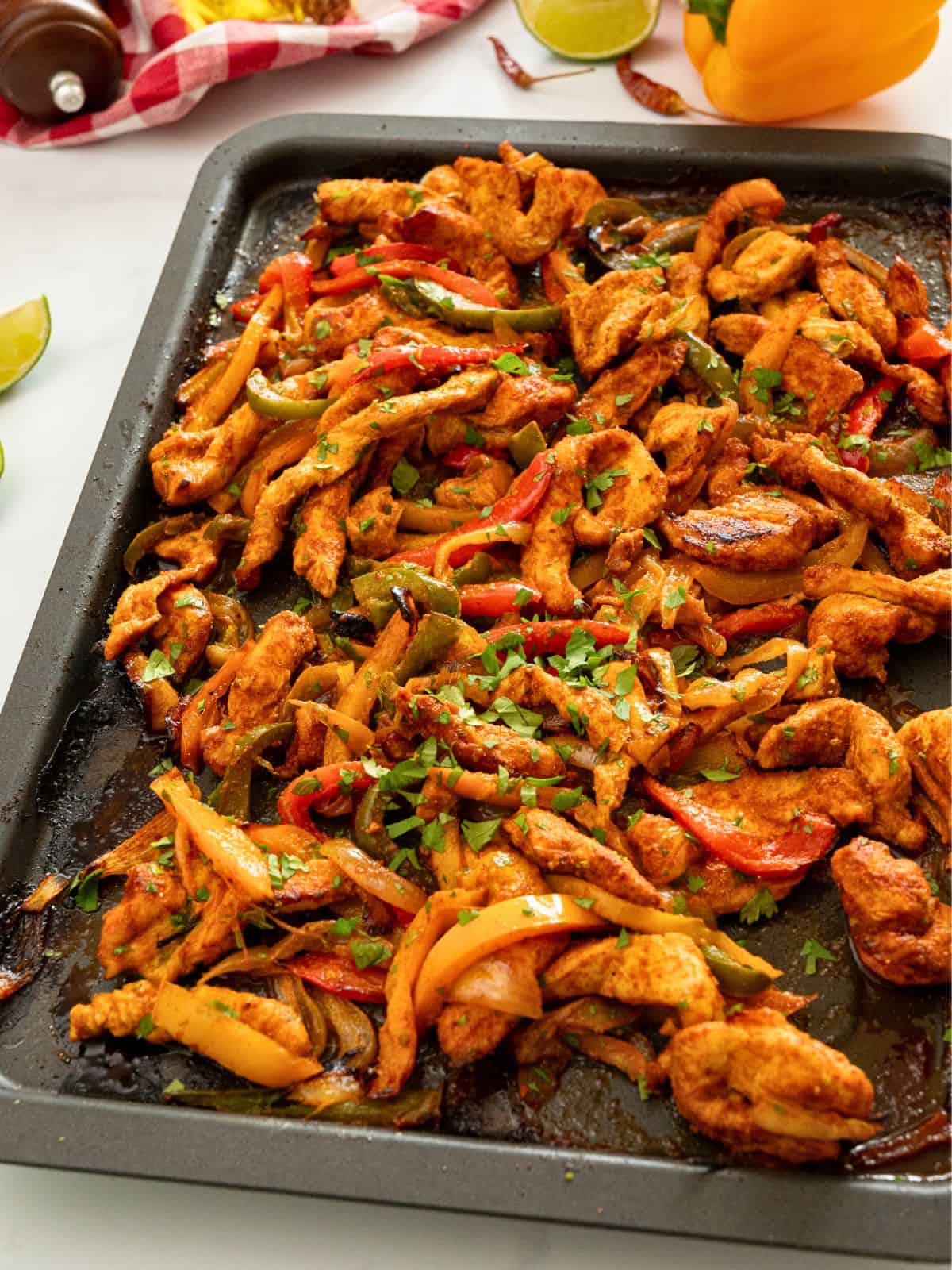 Chicken and peppers with onions roasted on sheet pan topped with lime zest with cilantro.