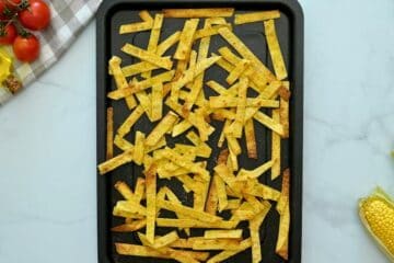 Baked crispy corn tortilla stirps on baking sheet after being coated in oil, seasonings, and baked until crispy.