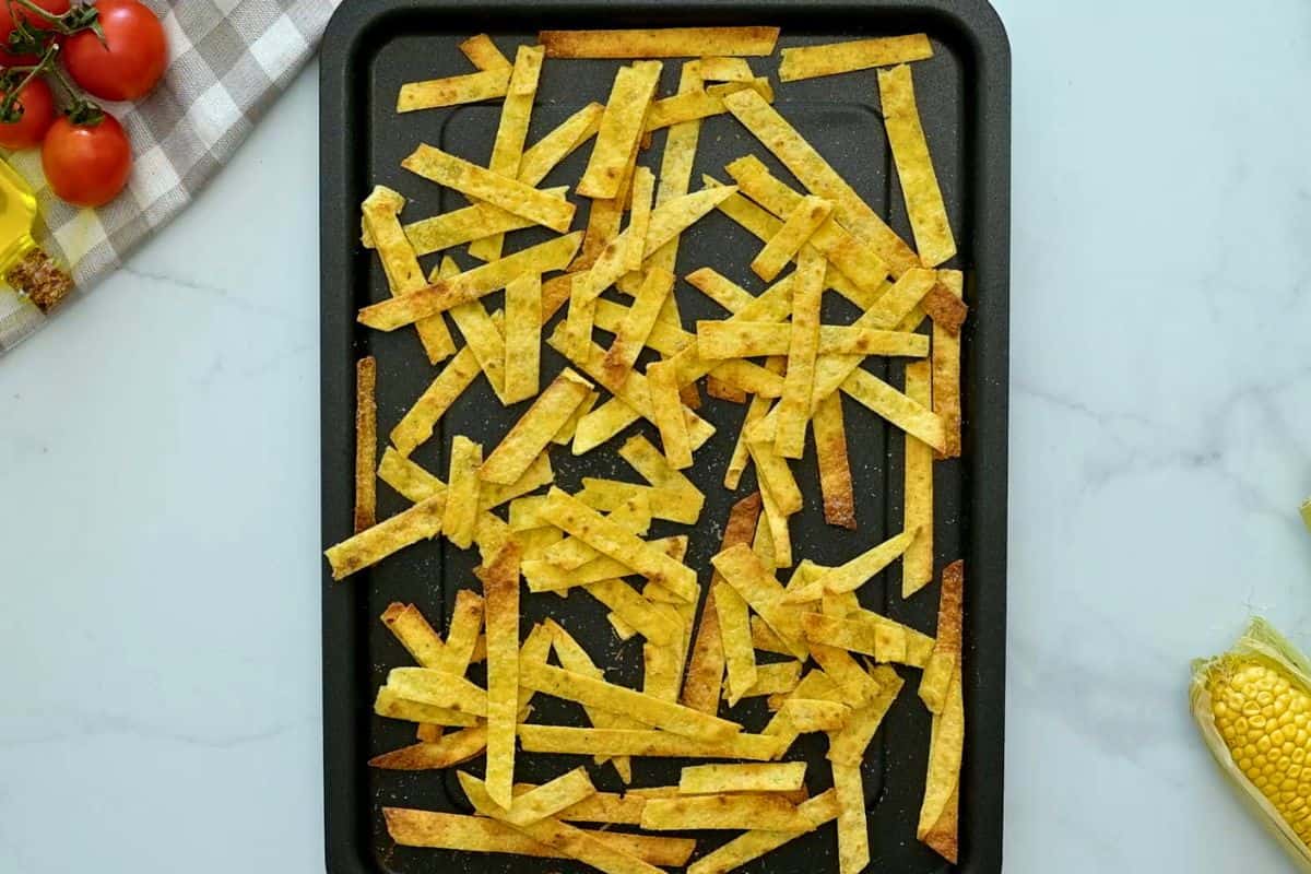 Tortilla Soup Crockpot Recipe Baked crispy corn tortilla stirps on baking sheet after being coated in oil, seasonings, and baked until crispy.