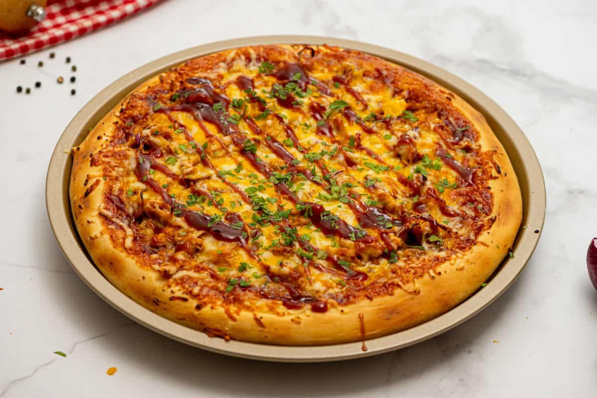 Recipe BBQ Chicken Pizza Baked pizza on pizza pan made with shredded BBQ chicken, cheese, and BBQ sauce.