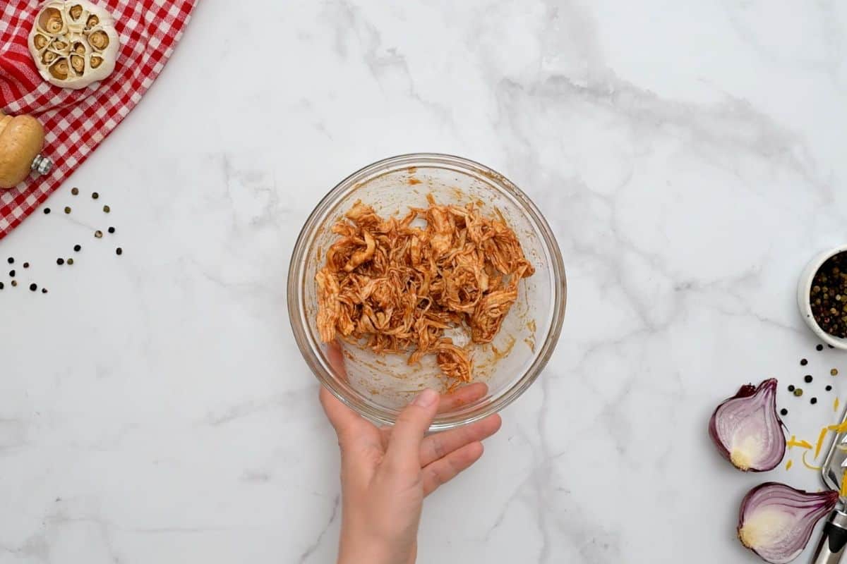 Barbecue Pizza Recipe Shredded chicken in bowl tossed with a bit of BBQ sauce for base of BBQ pizza.