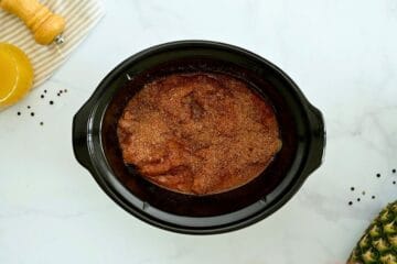 Pineapple juice, chicken breasts, and sweet and smoky dry rub layered together in crockpot before slow cooking.