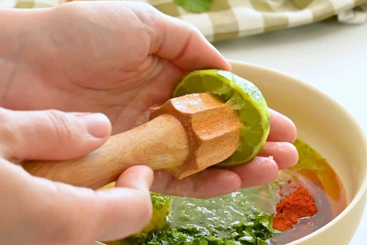 Cilantro Lime Marinade Lime being juiced over small bowl for cilantro lime marinade for chicken.