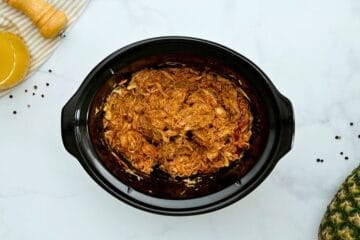 Shredded chicken breasts in slow cooker tossed with BBQ sauce.