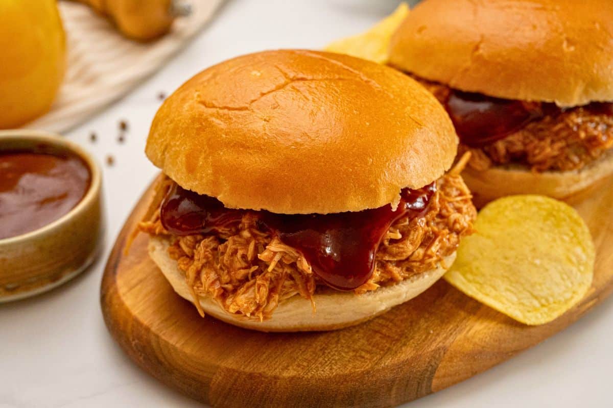 Crockpot BBQ Chicken piled on toasted bun served next to potato chips.