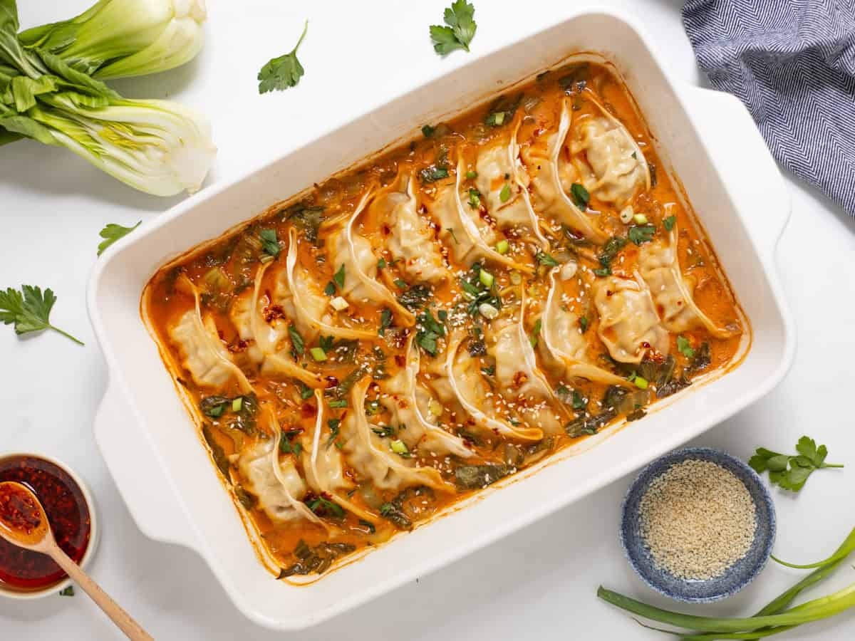 Frozen Goya Dumplings baked in curry-soy coconut broth with sliced bok choy topped with chili crisp, green onions, and sesame seeds.