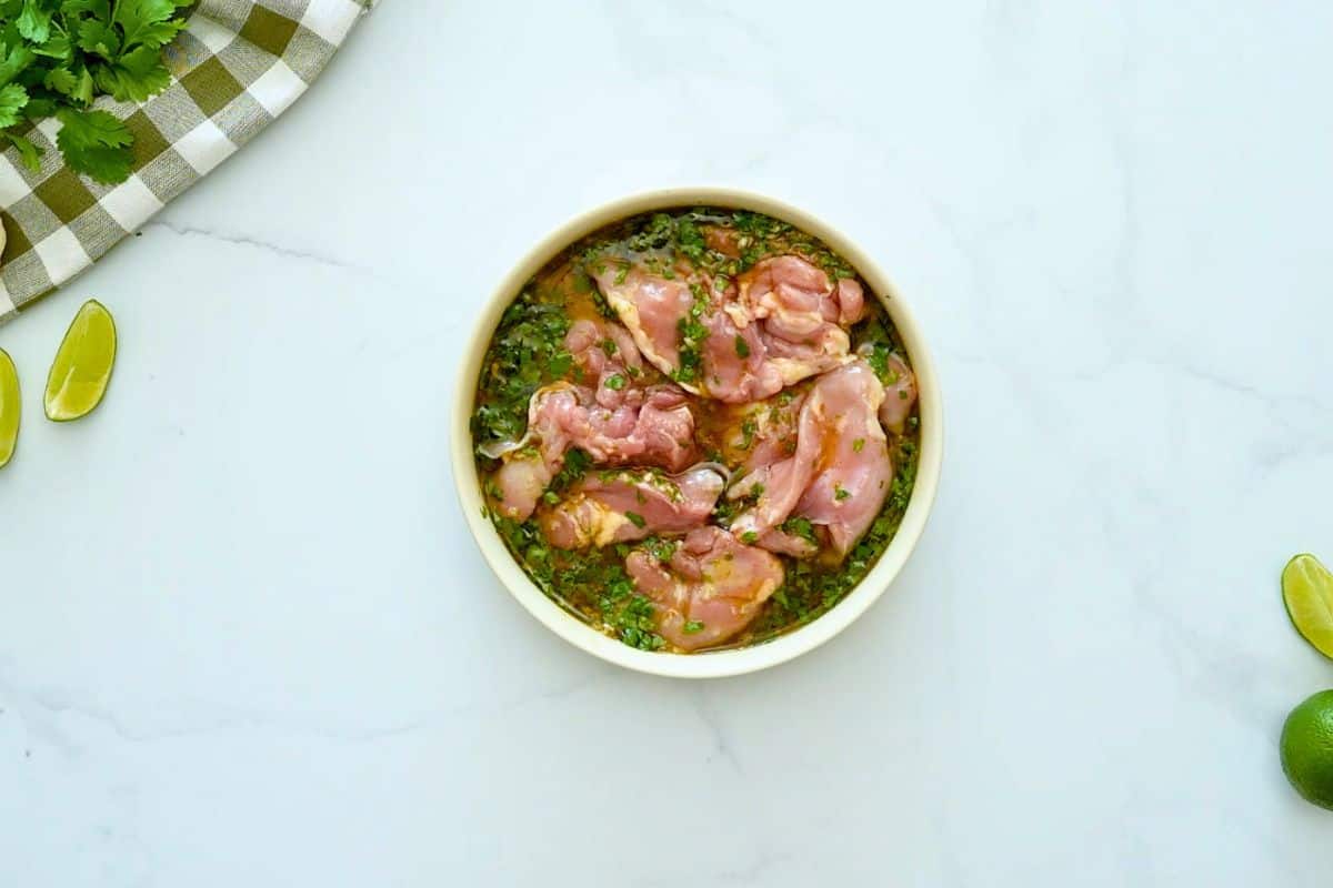 Cilantro Lime Marinade for Chicken Chicken thighs in shallow bowl with honey, olive oil, garlic, cilantro, and lime zest and lime juice marinade.