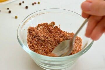 Brown sugar, salt, and dry spices being mixed in small bowl for dry rub for pulled chicken.