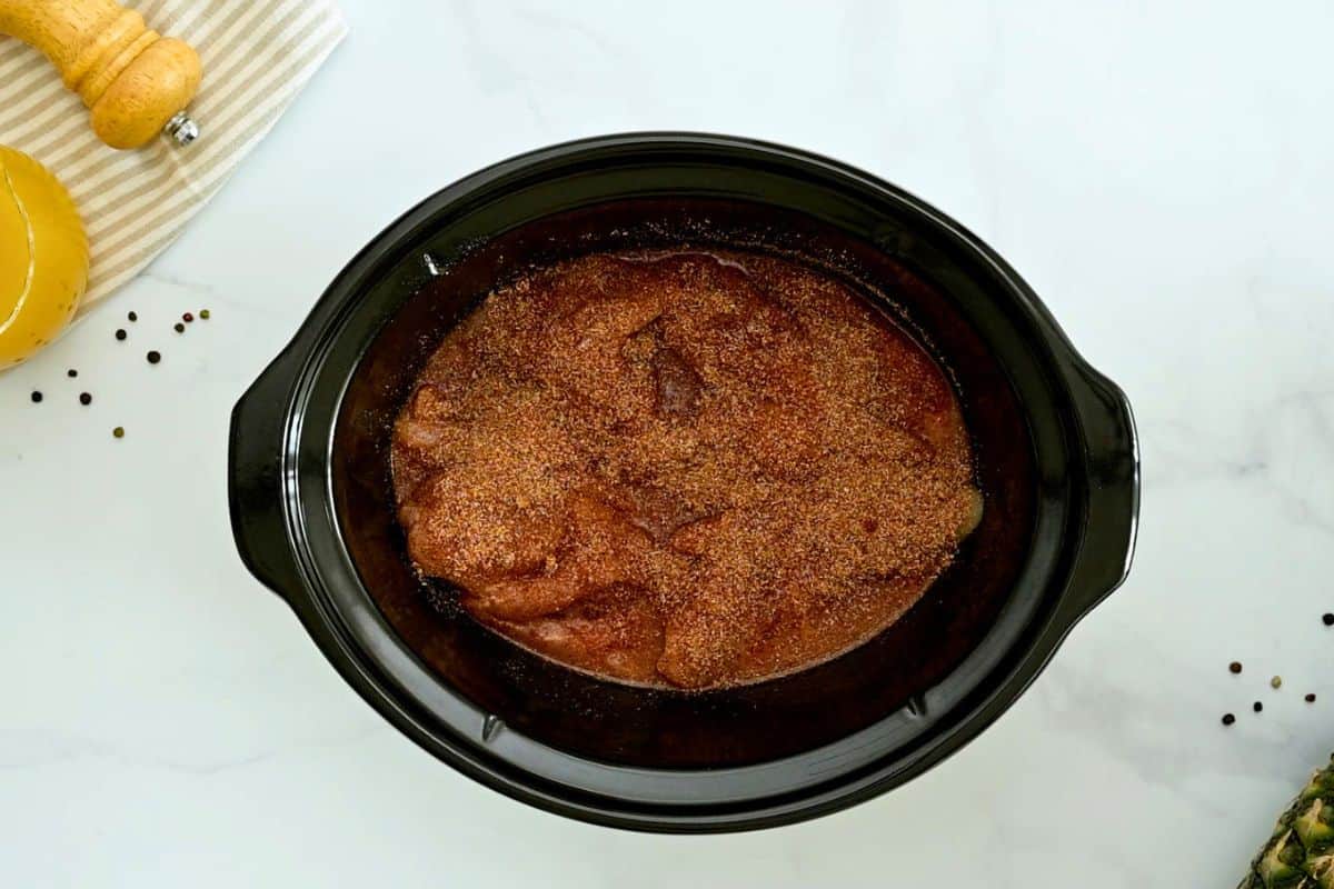 Slow Cooker Shredded BBQ Chicken Chicken breasts, pineapple juice, and dry rub seasoning layered in crockpot for pulled chicken recipe.