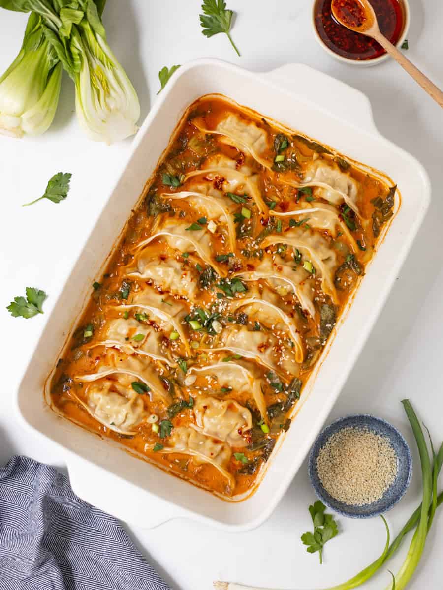 Frozen Goya Dumplings baked in curry-soy coconut broth with sliced bok choy topped with chili crisp, green onions, and sesame seeds.