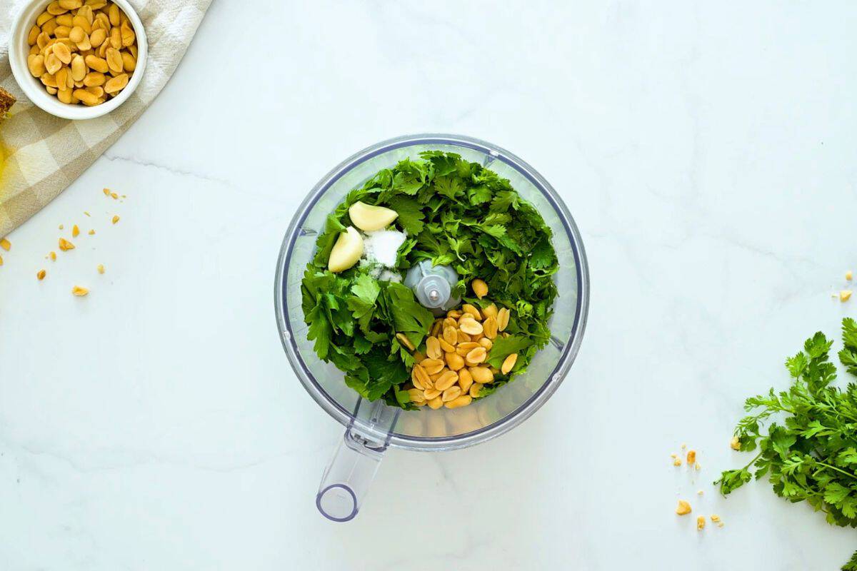 Easy Cilantro Pesto for Chicken Cilantro, parsley, peanuts, garlic cloves and salt in base of food processor.