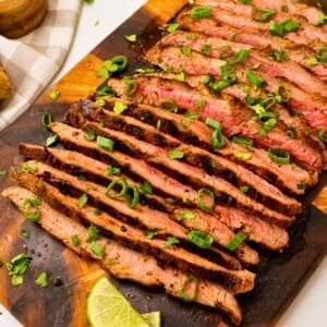 Garlic soy grilled flank steak sliced against the grain topped with cilantro, green onions, lime slices.