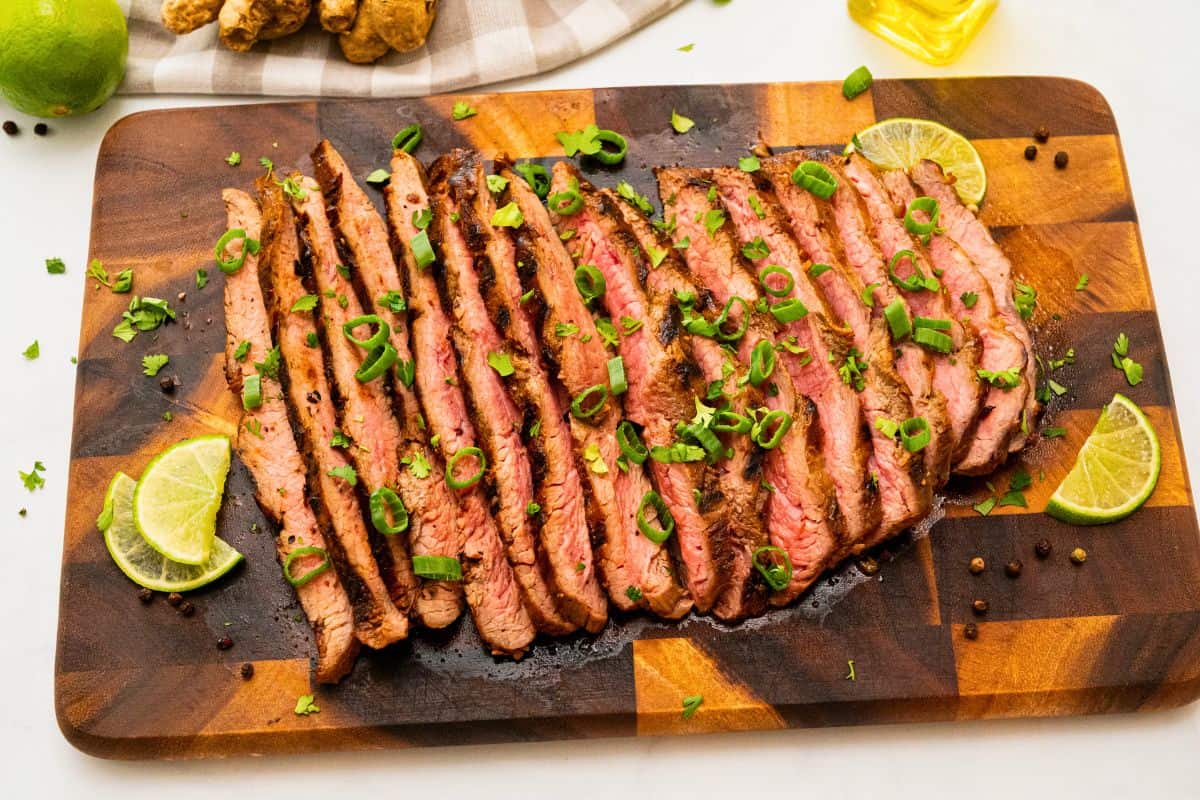 Marinated Flank Steak Marinated grilled flank steak sliced against the grain topped with cilantro, green onions, lime slices.