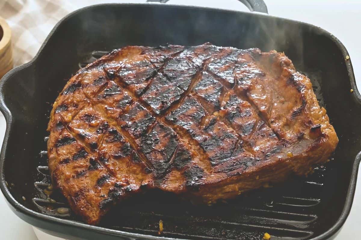 flank steak on grill Marinated flank steak on grill plate partially grilled.
