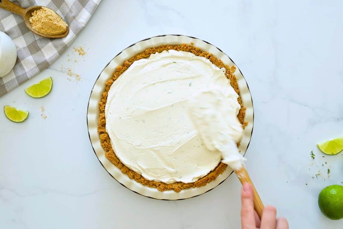 Key Lime Pie Recipe without Cool Whip Spatula spreading the no bake key lime pie filling into homemade graham cracker crust.