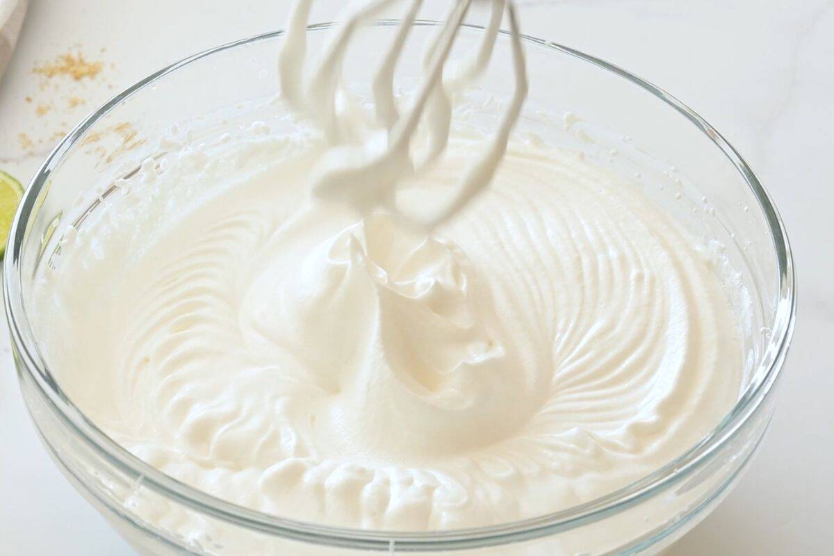 key lime pie recipe with sweetened condensed milk Mixing bowl with beaters showing softly whipped heavy cream holding gentle peaks.
