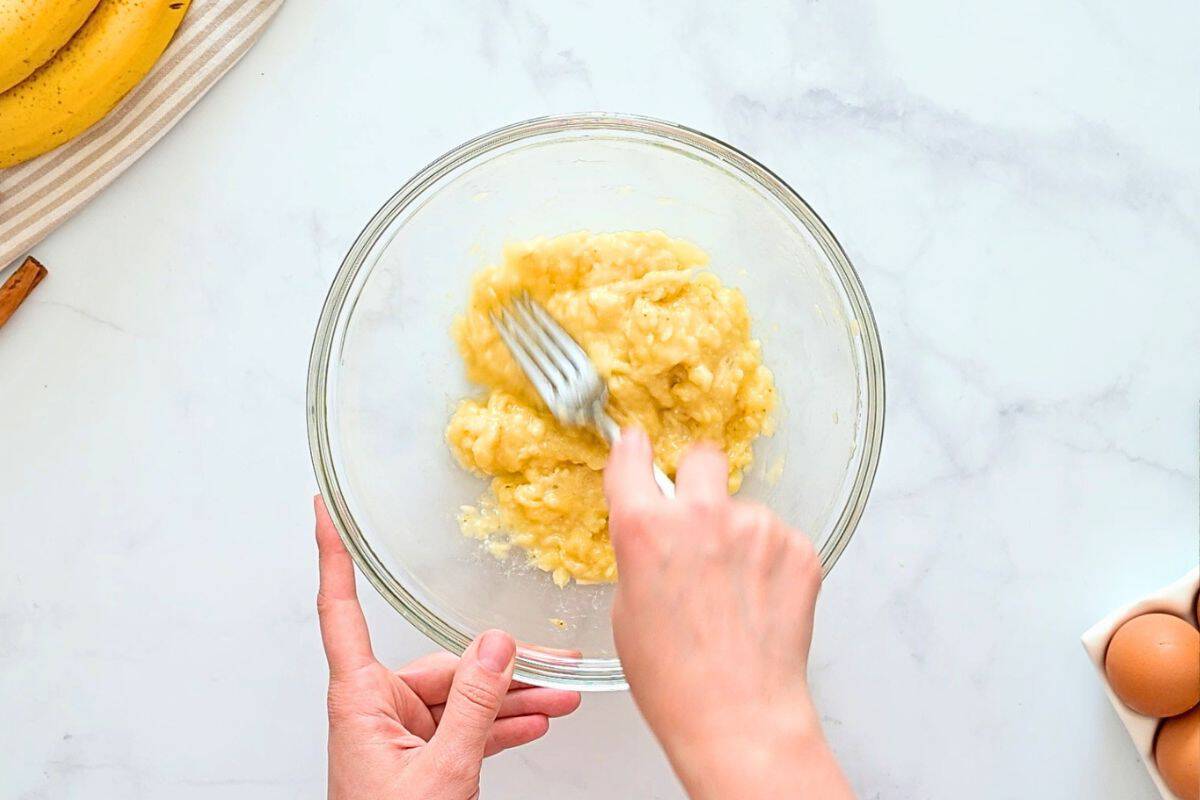 Zucchini Bread with Banana Fork mashing ripe banana in large mixing bowl.