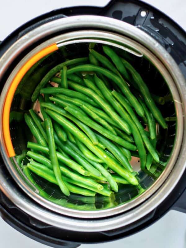 Steamed fresh green beans inside a steamer basket inside the inner pot after pressure cooking.