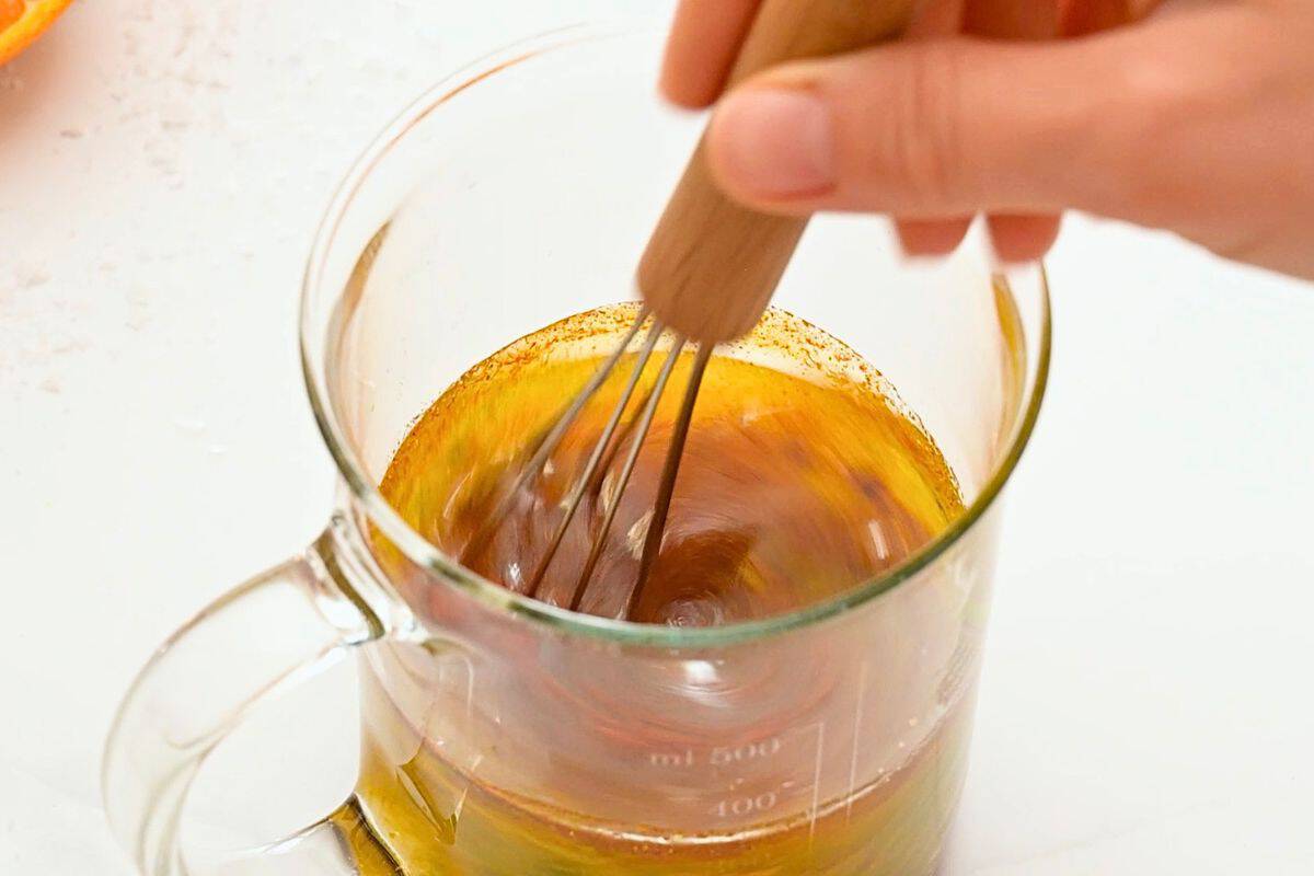 Orange juice, lime juice, garlic, paprika, and oil mixed together in small glass measuring cup.