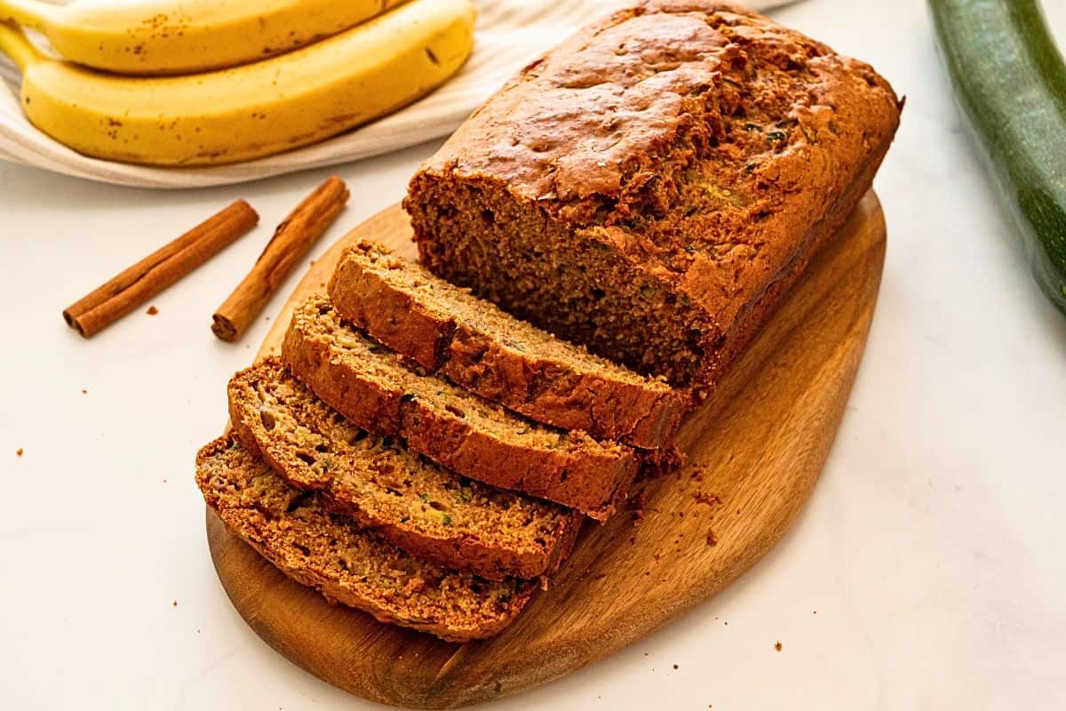 Zucchini and Banana Bread Sliced loaf of whole wheat zucchini bread made with mashed banana on cutting board.