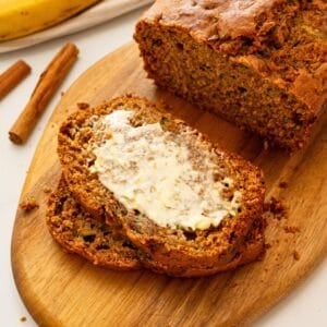 Loaf of Zucchini Banana Bread sliced into thick slices showing one slice with smear of butter.