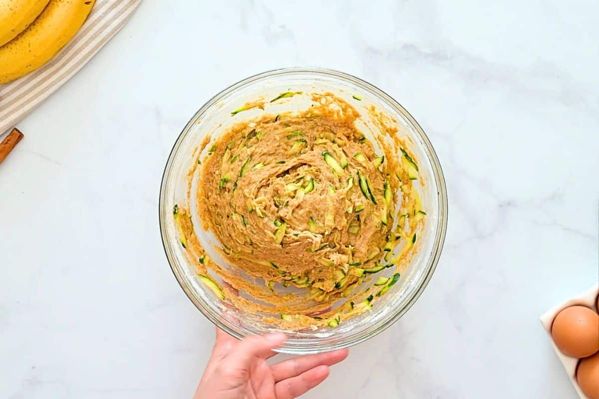 Zucchini Banana Loaf Shredded, squeezed zucchini folded into whole wheat flour quick bread batter in large mixing bowl.