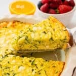 Spatula pulling out slice of crustless zucchini pie from pie plate.