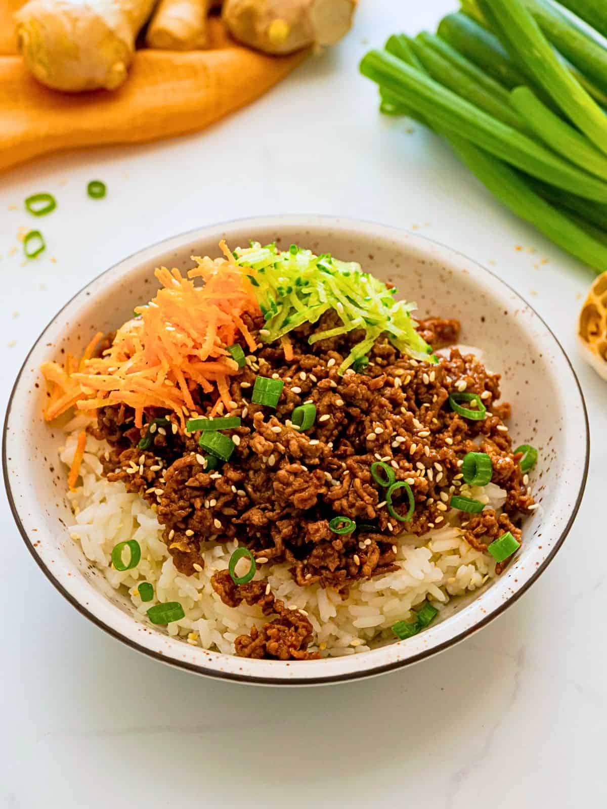 Korean flavored ground beef served over fluffy white rice and topped with grated carrots and cucumbers and sliced green onions.