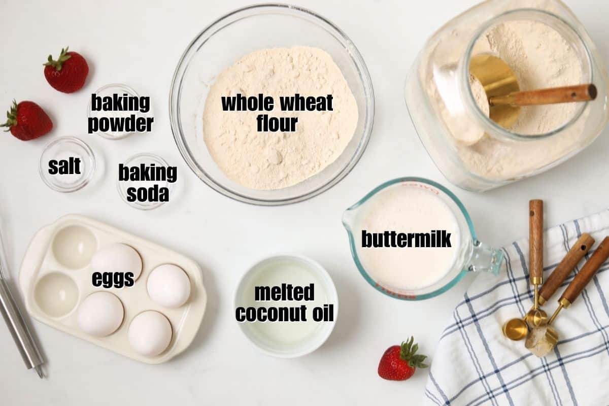 Easy Waffle Recipe with Whole Wheat Flour Whole wheat flour, buttermilk, eggs, melted coconut oil, and leavening agents on counter for wheat waffles.