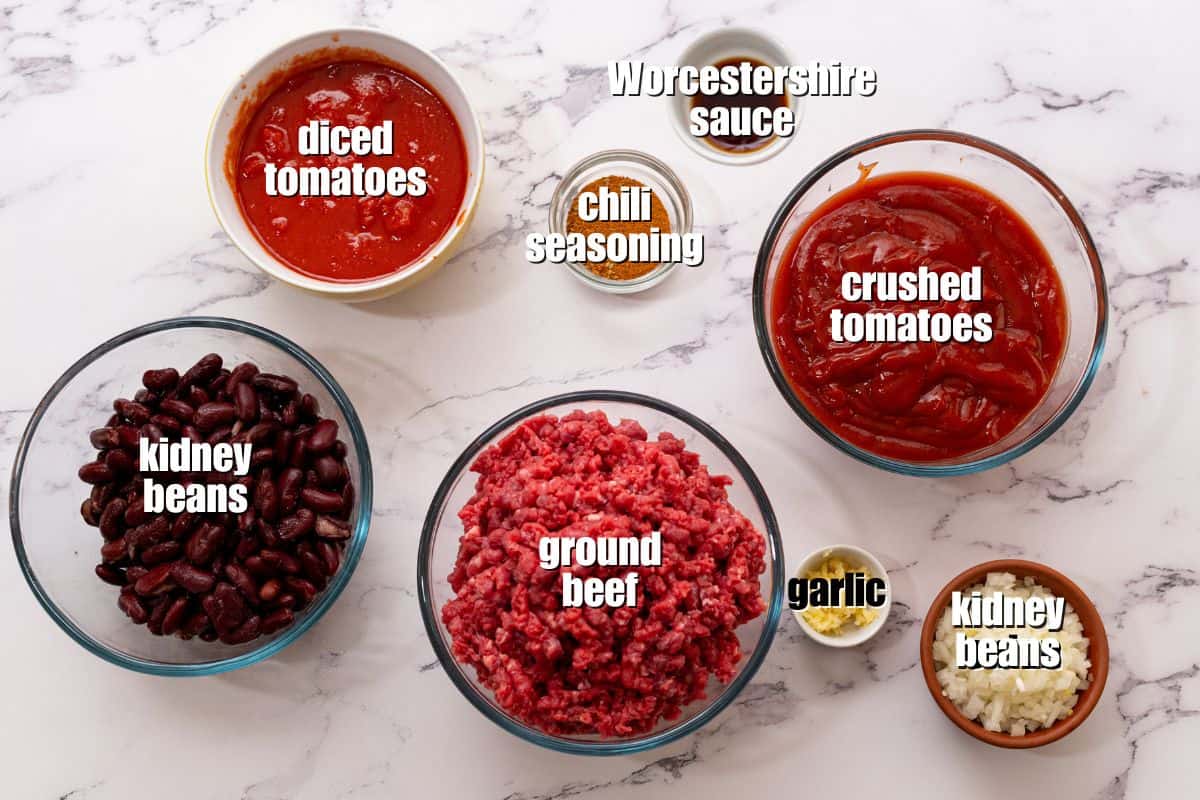 Beef and Bean Crockpot Chili Recipe Ground beef, kidney beans, tomatoes, onion, garlic, chili seasonings, and worcestershire sauce on counter for chili.