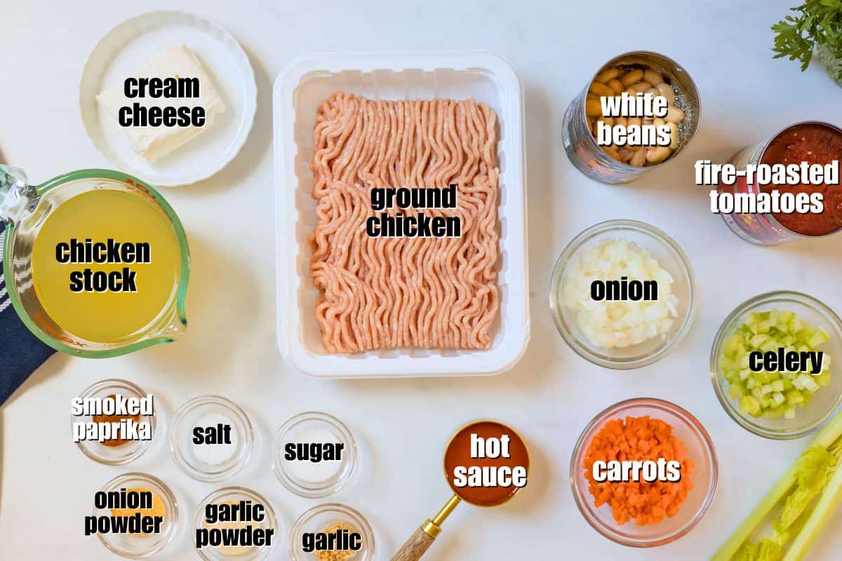 Ground chicken, spices, white beans, broth, creamy cheese, hot sauce, carrots, celey, onions, and seasonings labeled on counter.