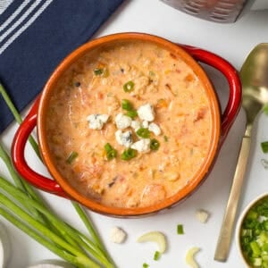 Instant Pot Buffalo Chicken Chili made with ground chicken dished out in red bowl topped with crumbled blue cheese.