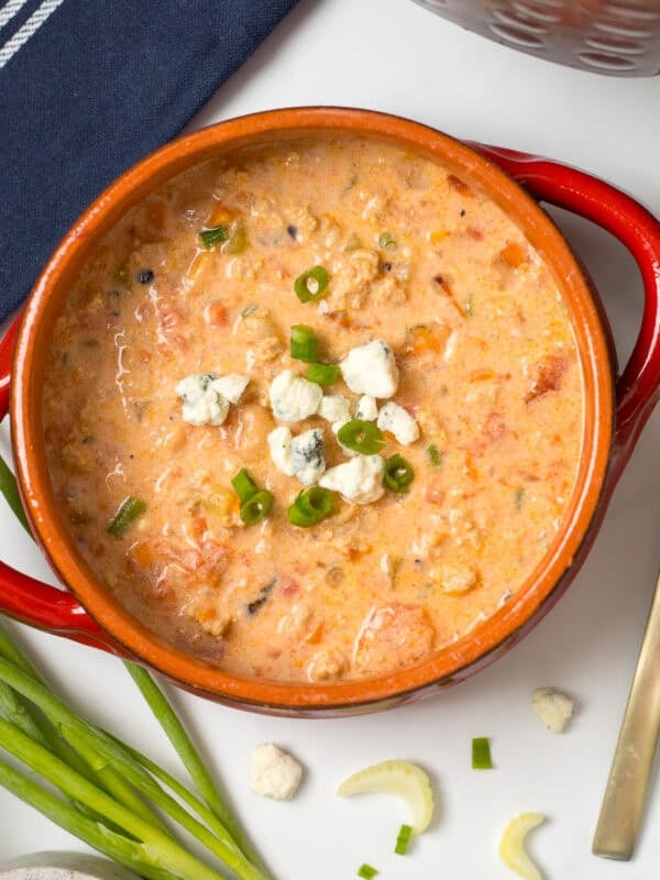 Instant Pot Buffalo Chicken Chili made with ground chicken dished out in red bowl topped with crumbled blue cheese.