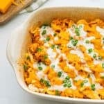 Buffalo flavored chicken and rice topped with cheese in casserole dish finished with drizzle of ranch dressing.