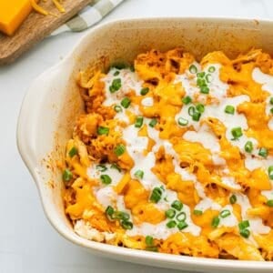 Buffalo flavored chicken and rice topped with cheese in casserole dish finished with drizzle of ranch dressing.