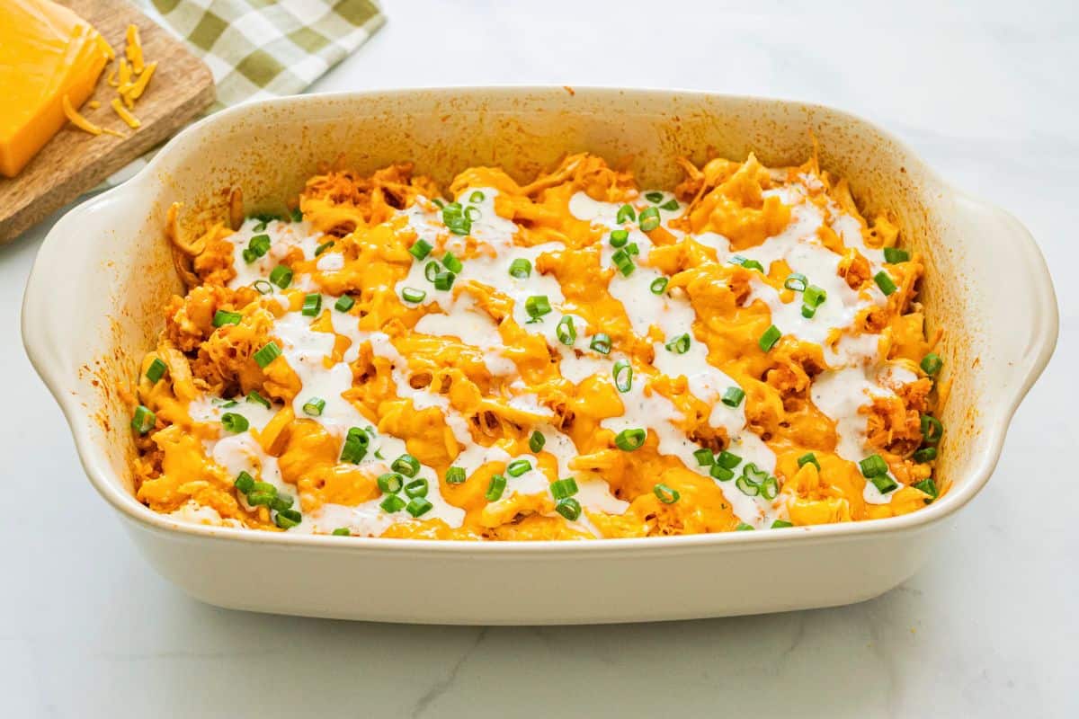Chicken and Rice Casserole with Buffalo Sauce Buffalo flavored chicken and rice topped with cheese in casserole dish finished with drizzle of ranch dressing.
