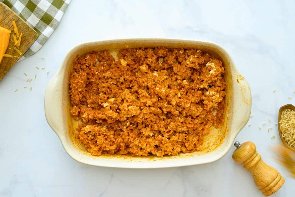 Plump rice mixed into buffalo cream cheese sauce in a baking dish.