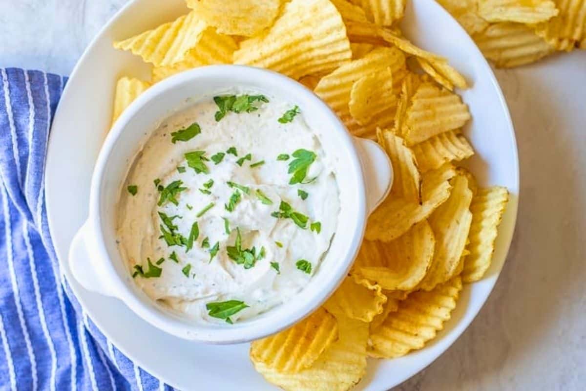 French Onion Chip Dip Recipe Homemade chip dip in small bowl next to wavy potato chips.